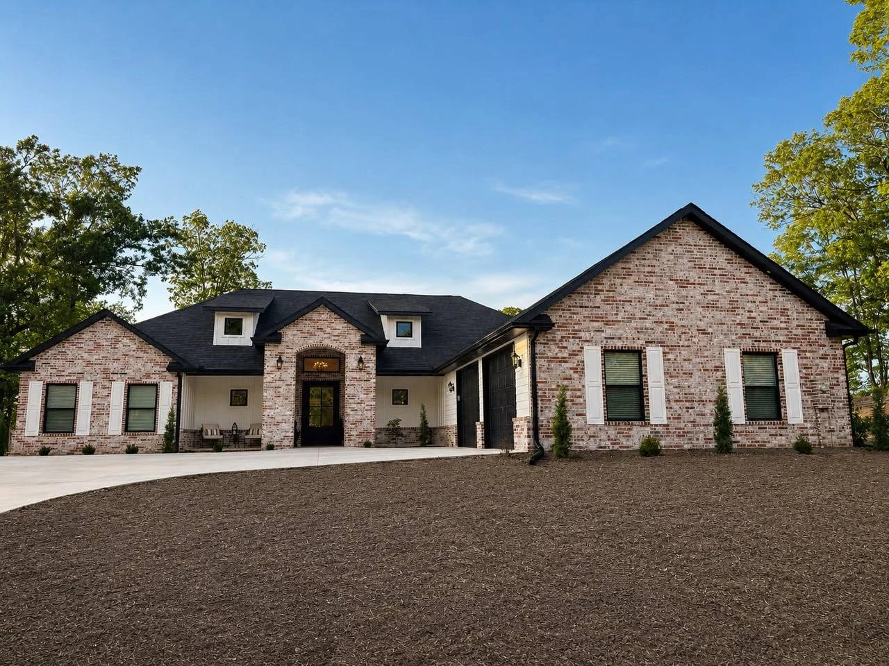 Brick single-story house with black roof, white shutters, and a large driveway